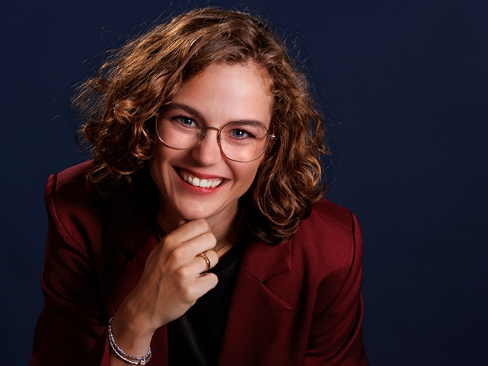 Zakelijke portretfoto van vrouw met krullend haar en hand onder haar kin